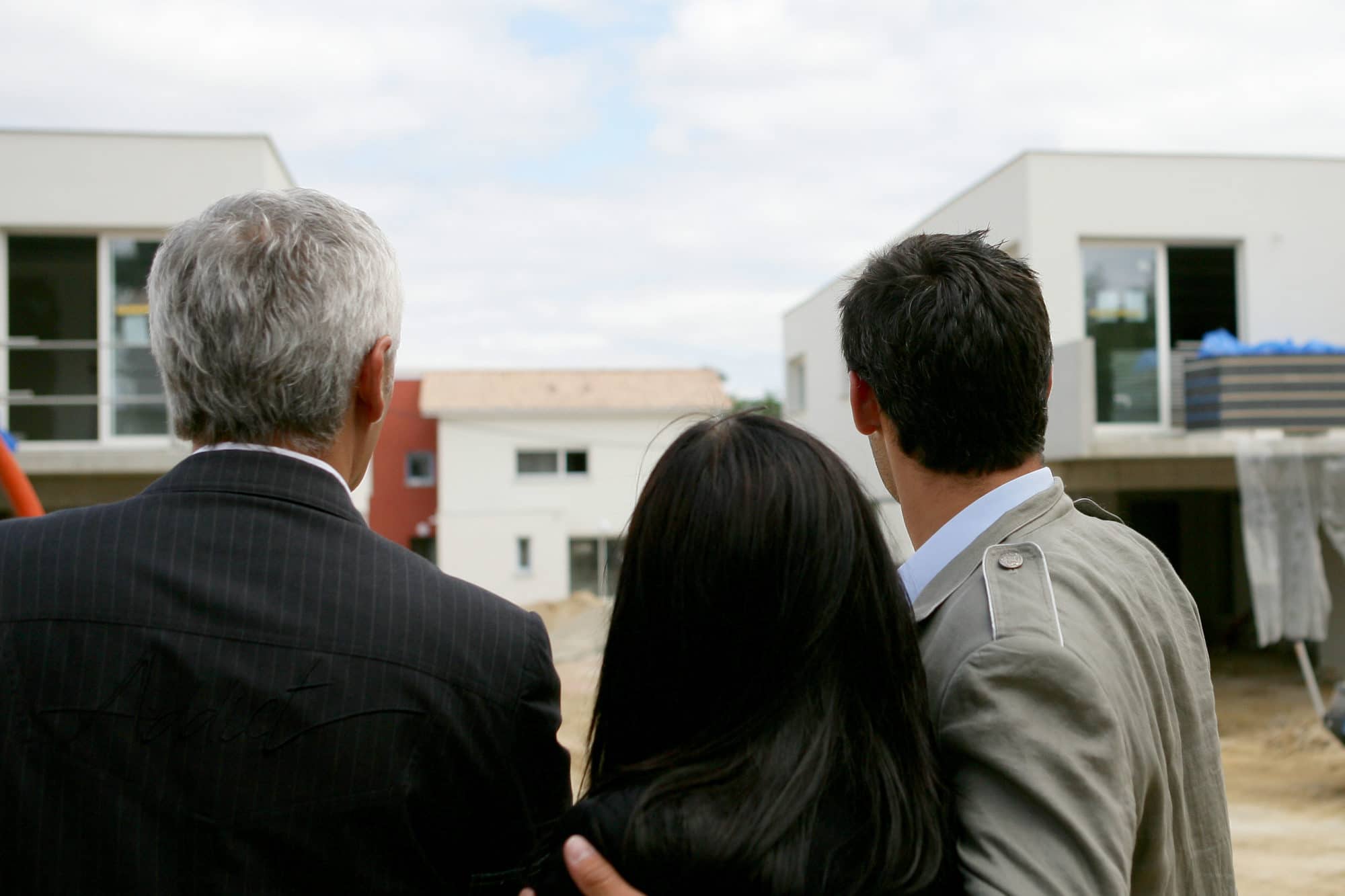 Real estate agent showing building under construction to man and woman