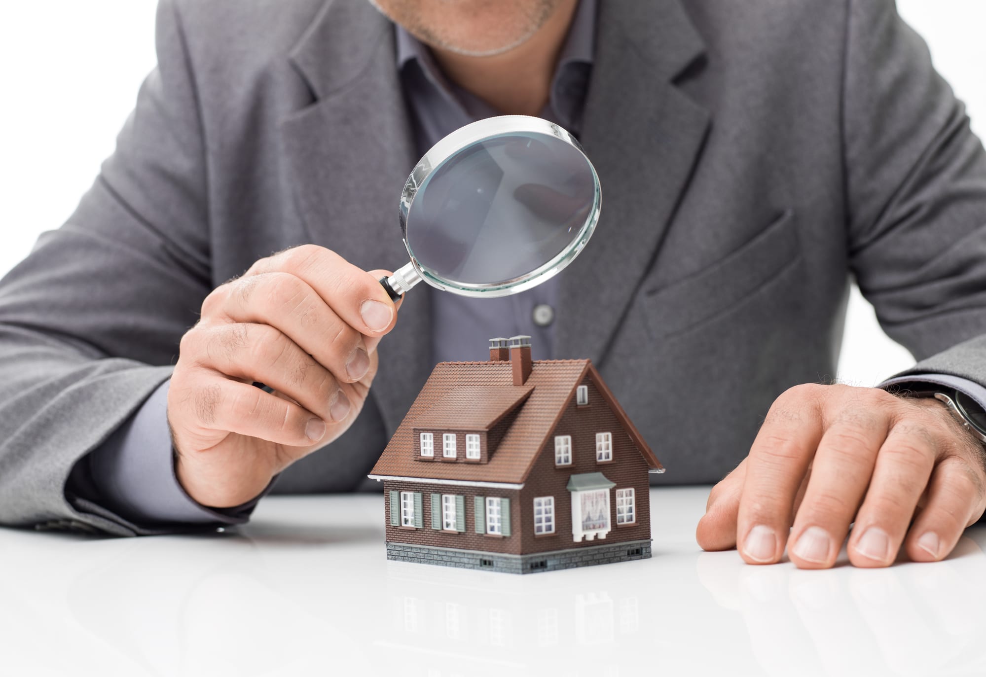 Man looking at tiny home through magnifying glass