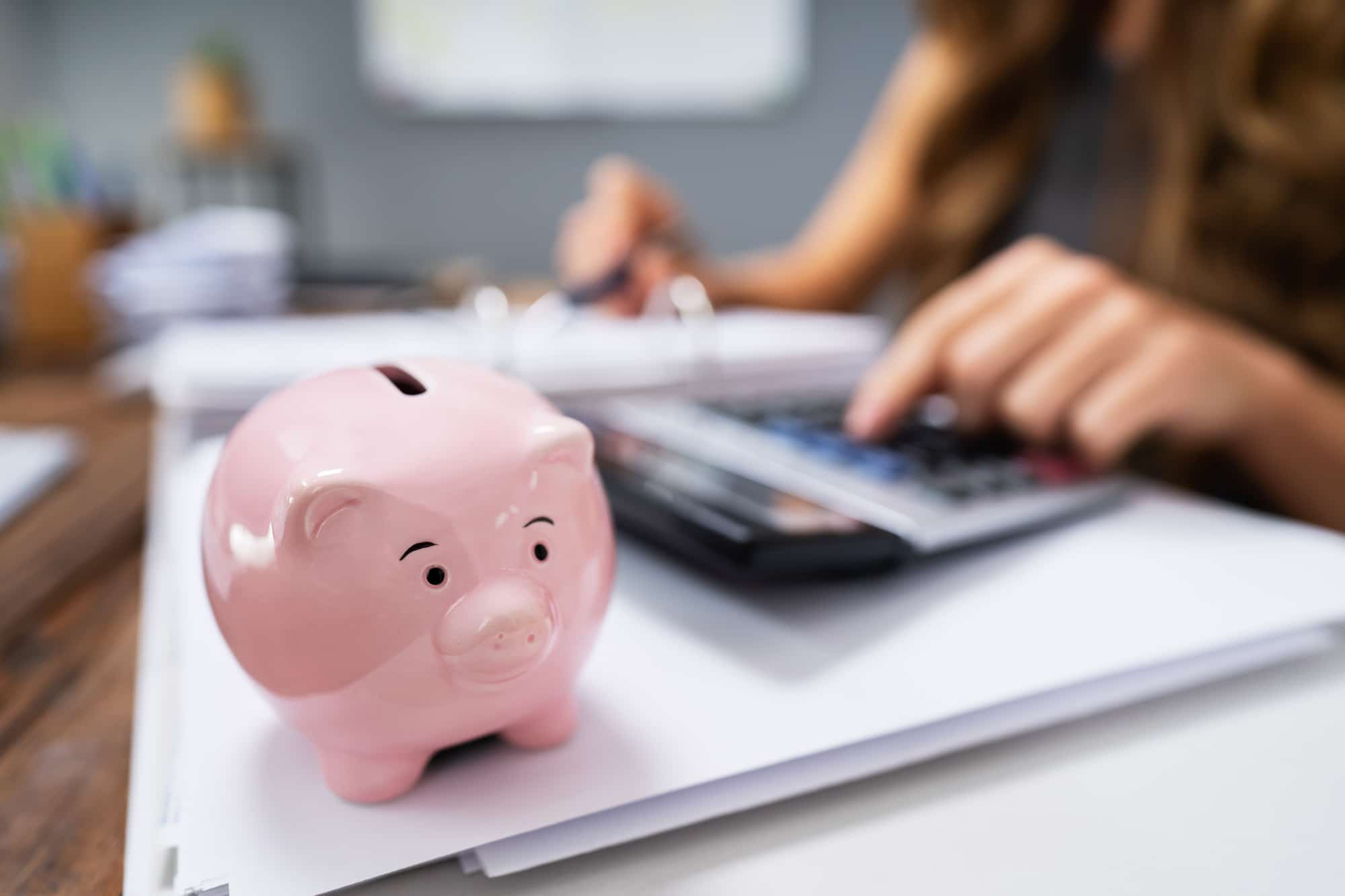 piggy bank on desk of woman looking at budget